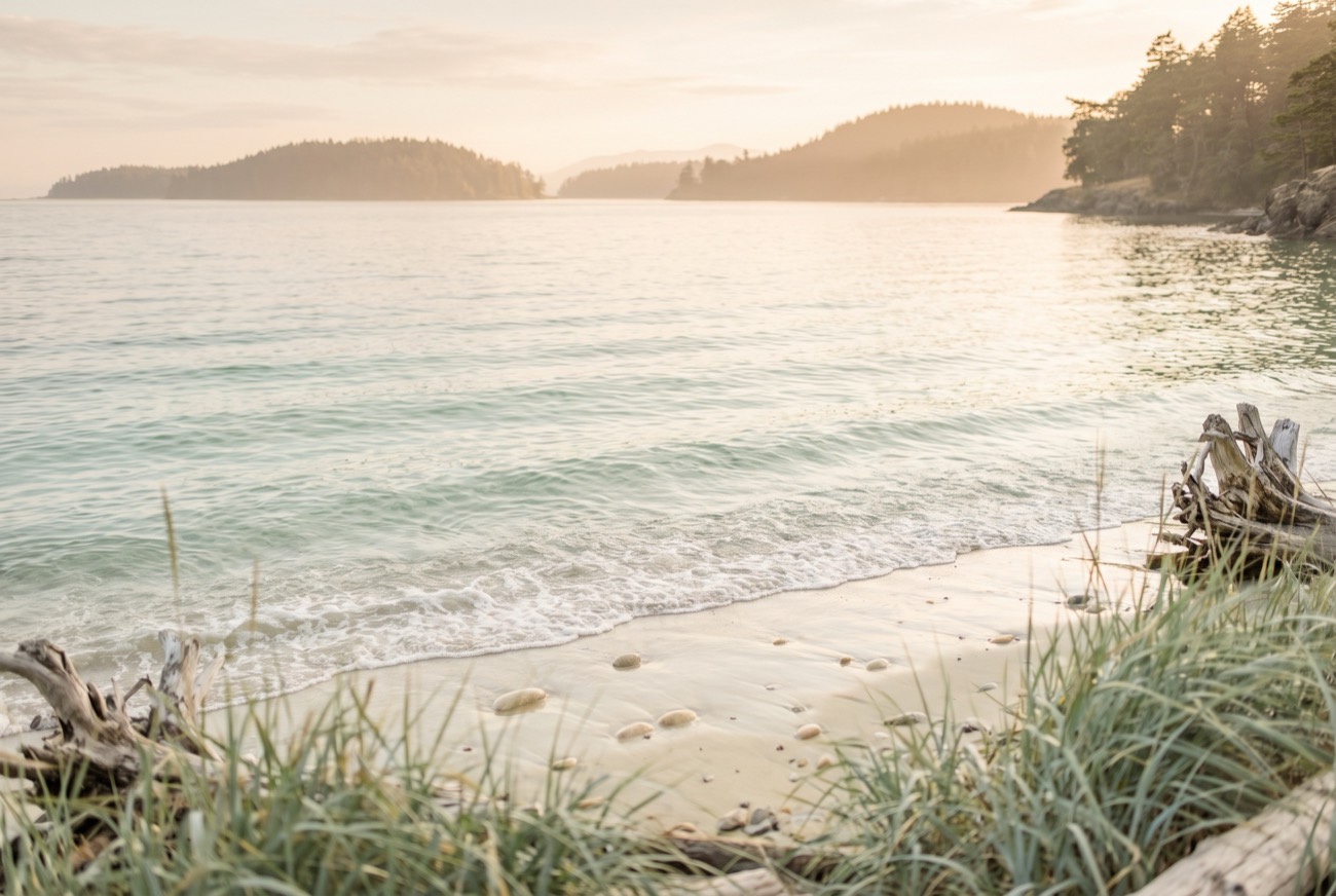 Shallow pale-green water over sand on the Salish Sea at golden hour